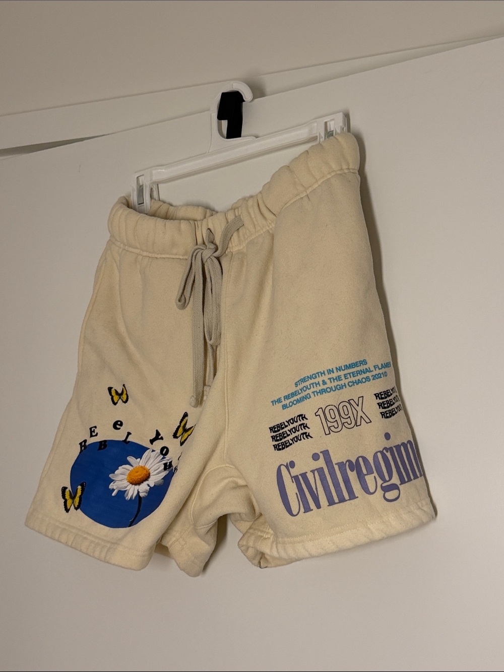 Cream Civilregim Graphic Athletic Shorts with Blue Daisy Accent